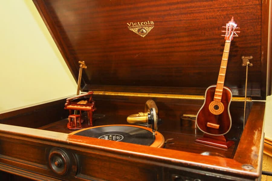 A vintage Victrola phonograph with miniature musical instruments displayed on top.