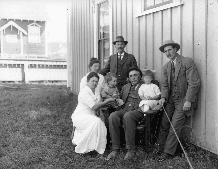 A group of six people, including adults and children, poses together outside a building in a black and white photograph.