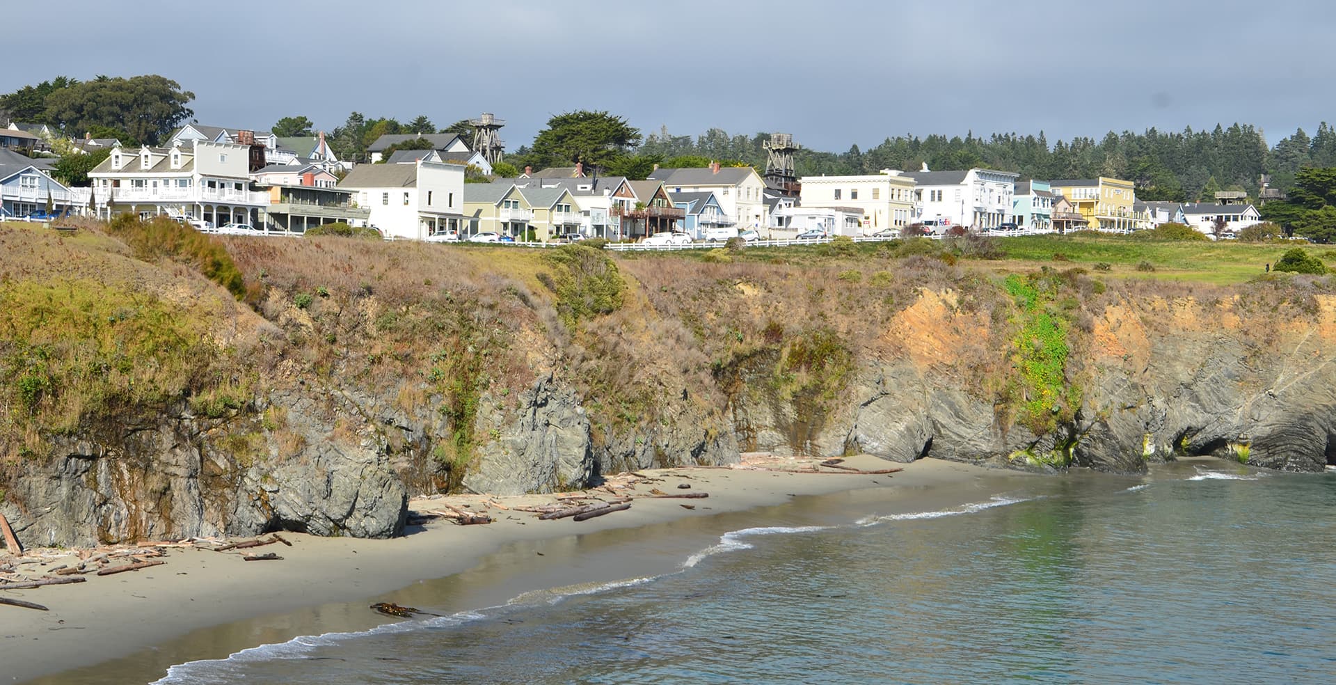 Coastal town perched above a rocky shoreline with scattered homes and greenery.