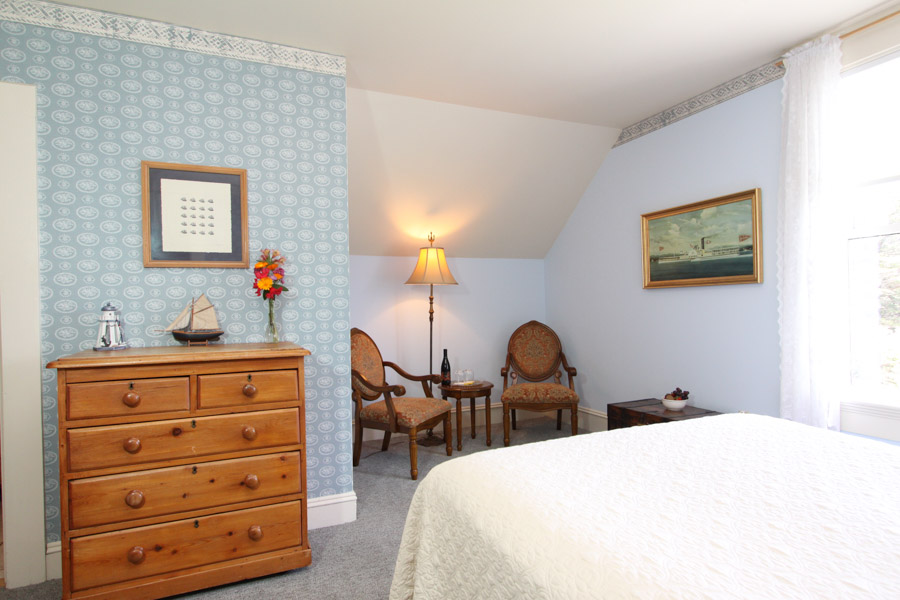 nautical room with bed, daybed, chairs, dresser and full bathroom